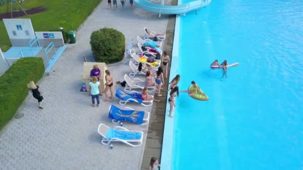 Domzale Slovenia 2015年6月スイミングプールの隣にデッキチェアが設置されています 女の子と男の子は楽しんでいて プールでぶらついています — ストック動画
