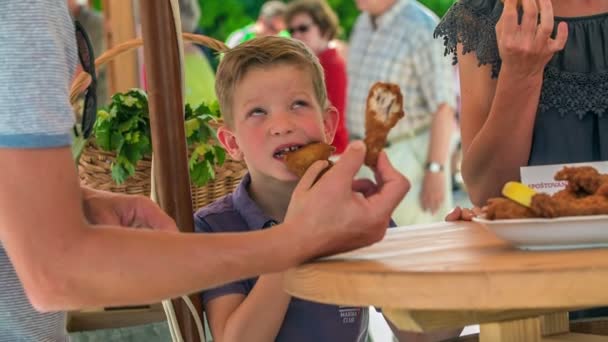 Domzale Slovenia 6月2018小さな男の子は 彼が食べているフライドチキンに噛もうとしています 家族全員が昼食のために揚げ物を食べています — ストック動画