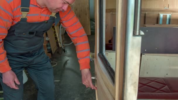 Ein Mann Überprüft Sorgfältig Die Oberfläche Der Tür Eines Nagelneuen — Stockvideo