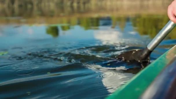 カヌーに乗っている間のパドルの動き 湖の水面を泳いでいる緑の葉もあります — ストック動画