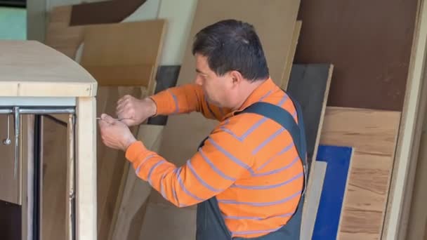 中年の木工職人は非常に専用に見えます 彼は新しいヴィンテージの木製車を作ろうとしている — ストック動画