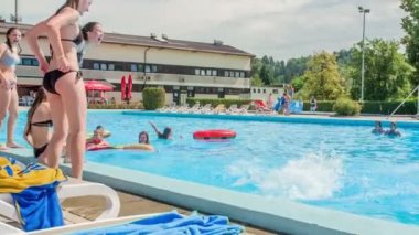DOMZALE, SLOVENIA - 20. Haziran 2015. Bir kız arkadaşını havuza itiyor ve kızlar buna gülüyor..