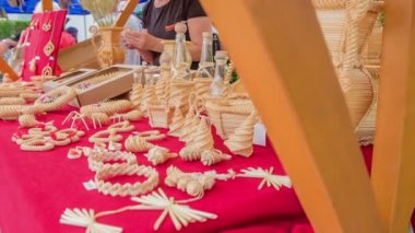 Bir müşteri ve bir satıcı tezgahta ahşap eşyalar hakkında konuşuyorlar. Hasır şapka festivalinde geçiyor..