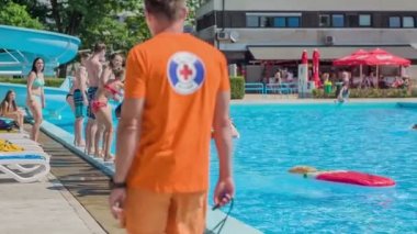 DOMZALE, SLOVENIA - 20. HAZİRAN 2015 Havuzda bir cankurtaran dolaşıyor ve gençlerin güvende olduğundan emin oluyor..
