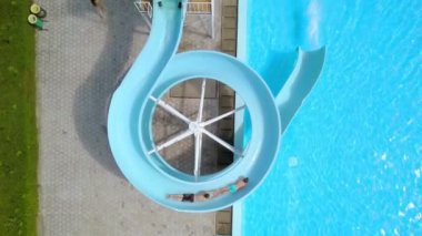 DOMZALE, SLOVENIA - 20. Haziran 2015 'te iki adam su kaydırağına birlikte inecekler. Biri diğerinin ayağına tutunuyor. Hava görüntüsü.