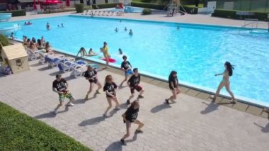 DOMZALE, SLOVENIA - 20. Haziran 2015 'te kızlar ve erkekler havuz kenarında hip hop koreosu yapıyorlar. Hava görüntüsü. Birkaç kız arka planda buluşup birbirlerine sarılıyorlar..