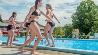 DOMZALE, SLOVENIA - 20. Haziran 2015 genç kızlar eğleniyor ve bir yüzme havuzunun kenarında dans ediyorlar. Sıcak bir yaz günü..