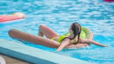 DOMZALE, SLOVENIA - 20. HAZİRAN 2015 Genç bir kız yüzme havuzunda şişme bir hava minderinde yatıyor ve güneşleniyor..