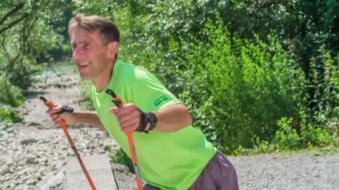 Olgun bir adamın doğa üzerinde yürüyüş direğiyle koşuşunun görüntüleri.