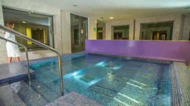 RIMSKE TOPLICE, SLOVENIA - 15. 2018 Eylül 'ünde bornoz giyen genç bir kadın Roma dizayn edilmiş güzel bir kaplıcada yüzme havuzunun önünden geçiyor..