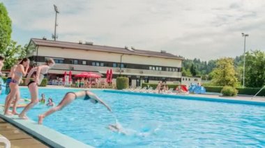 DOMZALE, SLOVENIA - 20. Haziran 2015 'te gençler zarif bir şekilde yüzme havuzuna atlıyorlar. Sıcak bir yaz günü..
