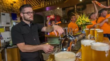 DOMZALE, SLOVENIA - 16. 2018 Temmuz 'unda bu bardaki bir barmen bu gece çok meşgul. Sürahilere bir sürü bira döküyor..