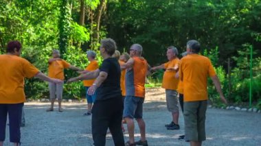 DOMZALE, SLOVENIA - 21. HAZİRAN 2015 Yaşlılar önce kollarını yana sonra da diğer tarafa hareket ettirirken bir egzersiz yapıyorlar..