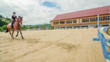 Bu çok yetenekli genç kız, binicilik seansı sırasında büyük bir arenada atlama alıştırması yapıyor..