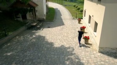 Bir adam büyük bir evin önünden geçer ve çocuklara yaklaşmaları için işaret eder ve çocuklar ona doğru koşmaya başlar..