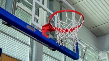 Top kenardan düşüyor ama yine de ağa değiyor. Çocuklar okulun spor salonunda basketbol oynuyorlar..