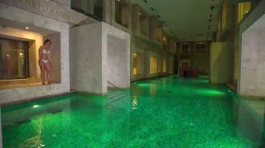 RIMSKE TOPLICE, SLOVENIA - 15. Eylül 2018 Bir kadın beyaz bir mayo giyiyor ve çok güzel bir kaplıcadaki boş bir havuza atlıyor..
