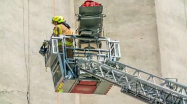 İtfaiyeciler binanın duvarına tırmanıp kendine zarar veren birini kurtarıyorlar. Sedye getiriyorlar..