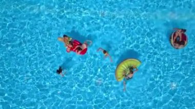 DOMZALE, SLOVENIA - 20. Haziran 2015 Gençler havuzda yüzüyor. Bazıları da güneşleniyor ve şişme yüzme minderlerinde dinleniyor..