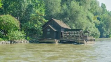 Eski bir vintage değirmeni hala çalışıyor. Bir nehir akıyor. Gün huzurlu ve güneşli..