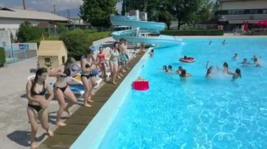 DOMZALE, SLOVENIA - 20. Haziran 2015 Kızları havuzun kenarında dans koreografisi yapıyor. Yaz mevsimindeyiz ve eğlenmeleri harika. Hava görüntüsü.