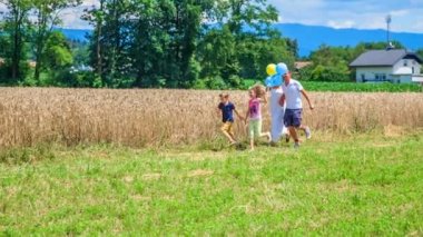 Genç ve güzel bir aile balonlarla koşuyor ve sonra da gitmelerine izin veriyorlar. Dışarıda güzel bir gün geçiriyorlar. Hava çok güzel..