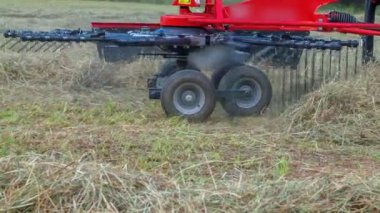 Bir adam dağların tepesinde saman hazırlarken döner tırmıklar yavaşça hareket eder..