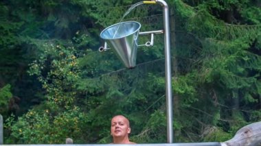 Bir adam jakuzide dinleniyor. Onun üzerinde büyük bir su dolu ve bir kez suyun etrafında bir kova içinde bir adamın kafasına düşer..