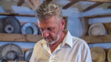 Dükkanda çalışan bir adam hasır şapkalardan birini rafa geri koyuyor..