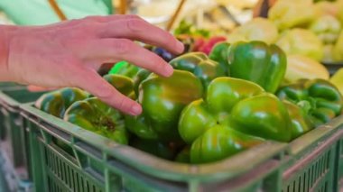 Genç bir anne yeşil biberlerden birini alır ve marketteki genç bir manavın eline verir..
