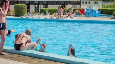 DOMZALE, SLOVENIA - 20. Haziran 2015 gençleri birbirlerine su sıçratıyorlar ve yüzme havuzunda eğleniyorlar. Güzel, güneşli bir gün..