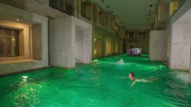 RIMSKE TOPLICE, SLOVENIA - 15. Eylül 2018 Genç bir yüzücü Roma tarzında tasarlanmış güzel bir kaplıcada rahatlarken ve yüzerken iyi vakit geçiriyor..