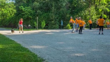 DOMZALE, SLOVENIA - 21. HAZİRAN 2015 Genç bir kadın köpeğini gezdirirken bir grup yaşlı insanın yanından geçiyor..