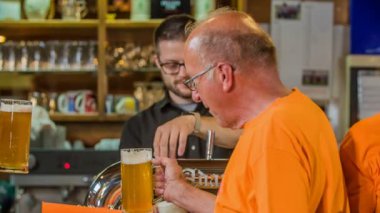 DOMZALE, SLOVENIA - 16. HAZİRAN 2018 İki destekçi bira ile kadeh kaldırmaya hazır. Arka tarafta da bir barmen var..