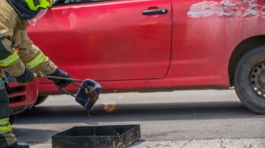 DOMZALE, SLOVENIA - 7. Temmuz 2018 Bir itfaiyeci bir ateş yakıyor ve onu arabanın kaputunun altına koyacak..