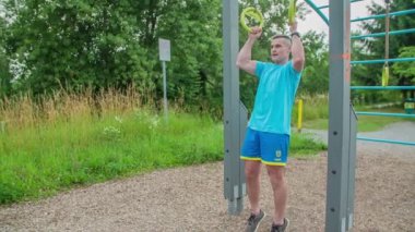 Açık havada çalışmak için güzel bir gün. An bazı güç egzersizleri yapıyor ve genç bir bisikletçi geçiyor..