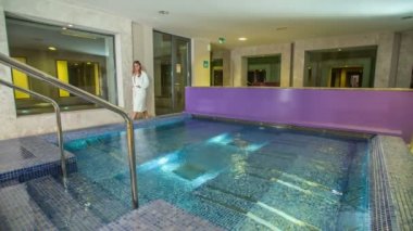 RIMSKE TOPLICE, SLOVENIA - 15. Eylül 2018. Genç bir kadın jakuzinin önünden geçiyor ve bornoz giyiyor..