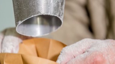 Bir adam çantayı açtığında bir un torbasına düştüğünü görebiliriz..