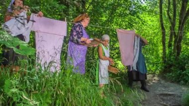 Yaşlı kadınlar daha yeni yıkanmış giysileri asıyorlar. Sıcak bir yaz günü..