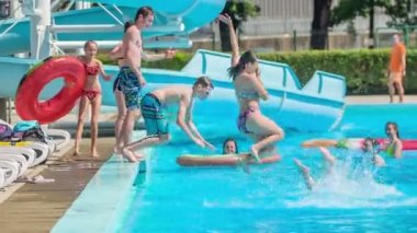 DOMZALE, SLOVENIA - 20. HAZİRAN 2015 Birkaç genç ya atlıyor ya da biri onları hazır olmadıkları zaman havuza itiyor..