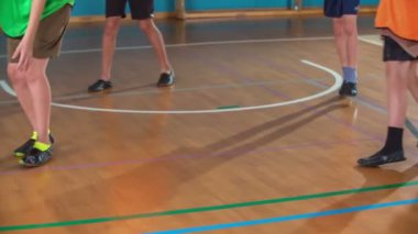 Bir öğrenci topu sedyeye doğru atıyor. Erkekler beden eğitimi dersinde basketbol oynuyorlar..
