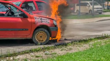 DOMZALE, SLOVENIA - 7. 2018 Temmuz 'unda kırmızı bir araba yanıyor ve itfaiyecilerden oluşan bir ekibin gelip yangını söndürmesi gerekiyor..