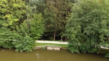 Bir sporcu muhteşem bir günde gölün etrafında bisiklet sürüyor. Hava görüntüsü.