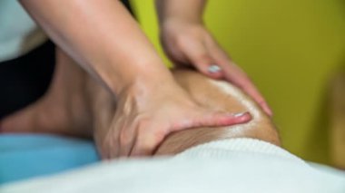 Bir masör nazikçe müşterisinin baldır kaslarını gevşetiyor..