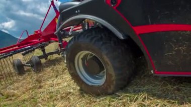 Bir çiftçi dik bir tepede yavaşça hareket ediyor ve saman hazırlıyor. Hava güneşli ve sıcak..