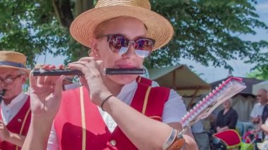 Bandodaki bir kadın hasır şapka festivalinde küçük siyah bir flüt çalıyor..