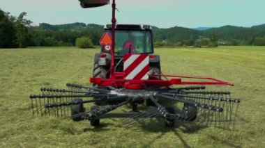 Döner tırmık makineleri yere iniyor. Bir çiftçi şimdi büyük bir çim tarlasında saman hazırlamaya başlayacak..