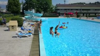 DOMZALE, SLOVENIA - 20. Haziran 2015 'te iki kız koşuyor ve aynı anda havuza atlıyorlar. Onlar eğleniyorlar. Hava görüntüsü.