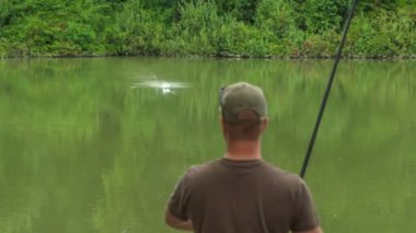 Bir balıkçı oltayı çabucak çeviriyor çünkü bir balık yakaladı..