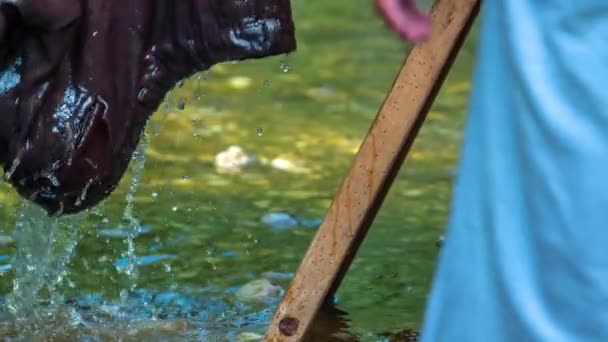 年配の女性が川の板の上で大きな服を洗っている — ストック動画